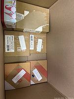 Cardboard box containing multiple smaller sealed boxes labeled with various product codes, some with partial labels torn off