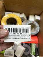 Close-up of a small white box with label showing product information and barcode, indicating 4-pack 3000K T10-4W lighting or electrical parts DC/AC 12V.