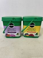 Two green containers of Miracle-Gro plant food, Bloom Booster and All Purpose, side by side.