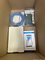Contents include a blue cable, green phone case in packaging, and black tablet or e-reader protective case.