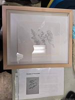 Framed ink artwork titled 'Talisman' with accompanying documentation beneath it.