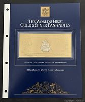 Front view of the gold and silver foil banknote in its display folder, showing the title and official insignia of Antigua and Barbuda.