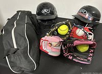 Assorted baseball and softball gear including helmets, gloves, balls, and a carrying bag.