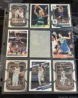 Photo shows 8 NBA basketball trading cards laid out on a grid with players including Trae Young, Larry Bird, Brandon Ingram, Patrick Ewing, Julius Randle, and Paul George.