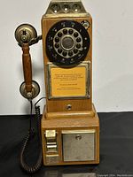 Photo of the full replica classic city call payphone showing wood body, rotary dial, attached handset, coin slots, and metal coin return section.