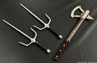 Top-down view of tomahawk axe and pair of sai together on black background