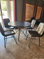 Dining table set with round dark wood top and four brown faux leather chairs in kitchen area, showing overall set and condition.
