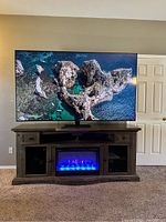 Front view of TV powered on displaying coastal rock scene on stand in living room