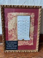 Full view of framed embroidery samples behind glass with descriptive plaque.