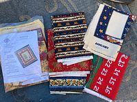 Photo shows folded fabric panels with visible holiday-themed patterns including numbers, stars, and borders. Paper instructions also visible.