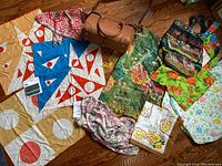 Overview showing all purses, scarves, and shawls arranged on a wooden floor, highlighting the variety and colors.