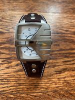 Front view of men’s Fossil wristwatch showing rectangular stainless steel case with unique design and white dial with numeric markers.