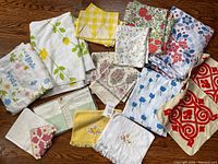 Lot of folded pillowcases, flat sheets and towels in various prints and colors, some with floral and geometric patterns.