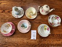 Overview photo of Sadler teapot, assorted teacups, creamers, and saucers on wood surface.