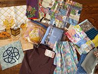 Overall view of diverse vintage fabric pieces laid out on wooden floor, including quilt blocks, solid and patterned fabrics.