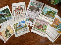 Full layout of all eight vintage calendar tea towels spread on floor showing their unique designs and date years.