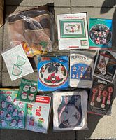 Overview photo showing various vintage Christmas craft kits sealed in original packages and bags alongside the brown mesh Thanksgiving tablecloth.