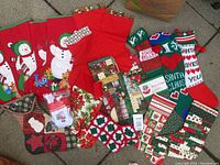 Lot of vintage Christmas stockings displayed on ground including red snowman stockings, green and red patterned knit stockings, patchwork quilted stockings, and printed stockings with Christmas themes.