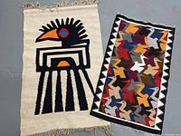 Two vintage wool rugs laid side by side on a floor. The left is a natural beige rug with a large stylized bird design in black, orange, and blue with fringe edges. The right is a colorful bird-patterned rug with black and white zigzag border and multiple birds in various colors.