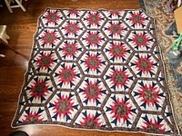 Full view of handmade quilted comforter with hexagon star pattern laid flat on floor
