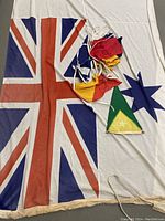 Large Australian ensign flag spread out with smaller multicolored nautical bunting flags and green and yellow triangular pennant displayed on top.