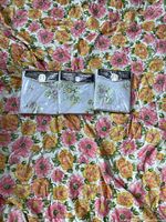 Three unopened new old stock Springmaid Daisy sheets with floral design, still in original packaging, placed on top of the comforter.