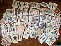 Large collection of vintage sewing patterns spread out showing the full assortment and envelopes with fashion illustrations.