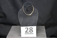 14KT gold triple-strand braided bracelet displayed on black necklace bust