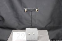 Photo showing the two pairs of gold earrings on display mounts, illustrating relative size and style.