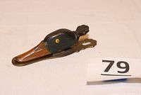 Front angle of antique cast iron duck head paper clip holder showing detailed paint and yellow glass eyes.