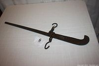 Full view of antique wrought iron hanging scale, showing entire length and hook details.