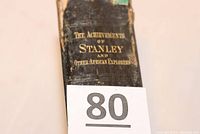 Front spine of the hardback book showing title 'The Achievements of Stanley and Other African Explorers' in gold text on worn black spine.