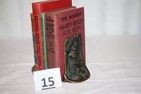 Full view of both bookends holding books on a white cloth surface, showing overall size and usage with books