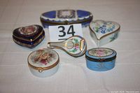 Six vintage Limoges porcelain dresser jars and boxes shown together on a tablecloth with lot number card 34.