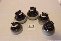 Top view of five vintage heavy duty ceramic electrical insulators showing brown tops and round shapes.