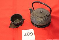 Set showing the teapot, cup on leaf-shaped saucer, on red surface