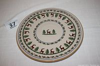 Full view of the pottery plate showing circular design with reindeer and tree motifs around the border and center.