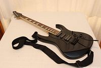 Full view of black MetAlien electric guitar showing body, neck, attached strap, and tremolo bar.