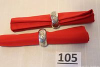 Two sterling silver napkin rings displayed on red napkins showing the overall appearance and size.