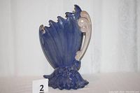 Front and side view showing curved butterfly wing shape with textured rose detail near base.