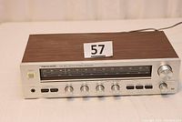 Front view showing the entire receiver with wood grain top and silver control panel with knobs and switches.