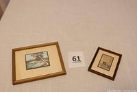 Both small framed hand-painted photographs shown side by side on a cloth surface with lot number 61 in between.