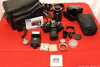 Full overview of the Vivitar camera lot including camera body, lenses, flash, camera case, bag, and assorted accessories laid out on a red surface.