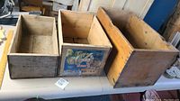 All three old wooden boxes placed side by side on a table showing differences in size and condition.