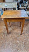 Front view of the small antique pine tavern table showing straight legs and patina on wood.