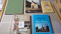 Five books arranged on table, titles related to Canadian heritage and history visible.