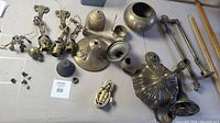 Top view of assorted vintage brass lamp parts laid on a table, showing lamp arms, fittings, and small components.