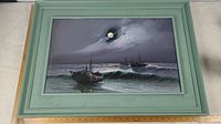 Full view of the framed painting showing the ocean with boats under moonlight.