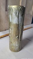 Photo showing front embossed bamboo and leaf design on tapered brass shell-shaped vase with patina and wear