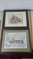 Two 19 x 24 inch framed train locomotive art prints shown side by side on white surface. One print shows a green Canadian National locomotive, the other a winter train station scene.